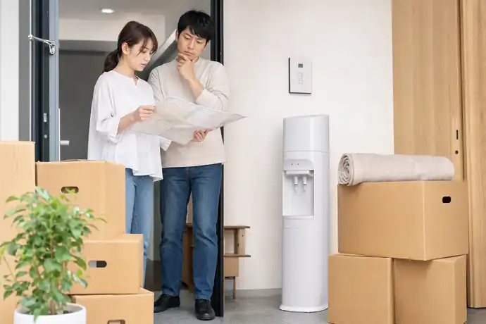 引っ越し準備中にウォーターサーバーの利用地域を確認する夫婦