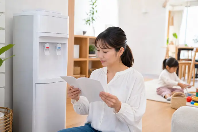 ウォーターサーバーの説明書を確認する保護者と安全に遊ぶ子どもの様子