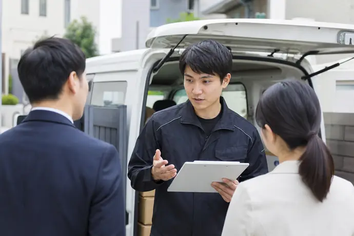 軽貨物車両と配送会社のサポート担当者を前に条件を確認するドライバーの場面