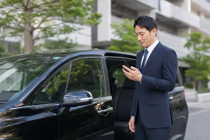 研修を受けたライドシェアドライバーが配車アプリを確認して乗務を始める場面