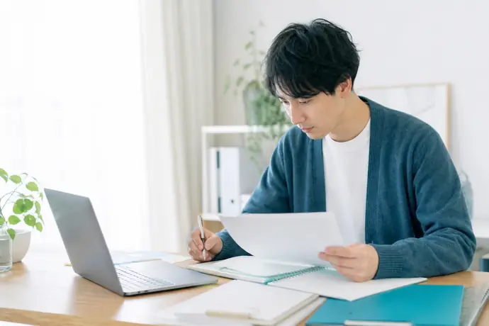 個人事業主が青色申告承認申請書と帳簿の準備状況を机上で確認している自然な仕事風景