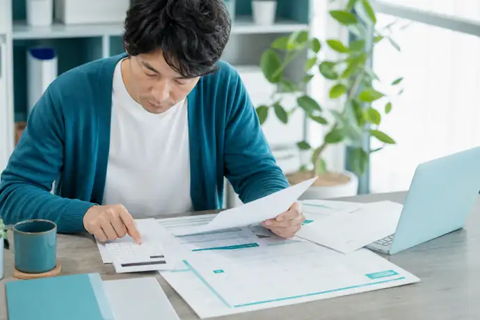 個人事業主が納税カレンダーと資金繰り表を見比べ予定納税の準備をしている自然な仕事風景