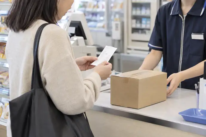 コンビニで荷物を預けた後に受付控えを確認する場面